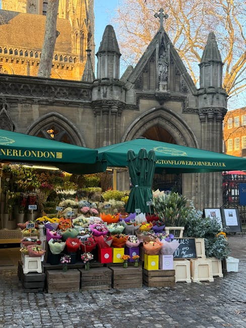 A vibrant flower stall set up in front of a historic stone building with gothic arches and ornate detailing, featuring an array of fresh flowers arranged in colorful bouquets wrapped in pastel and viv